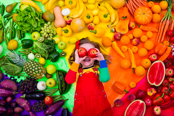 Healthy eating child with fruit over eyes, smiling.